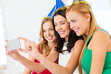 Image showing three smiling women in hats having fun with camera