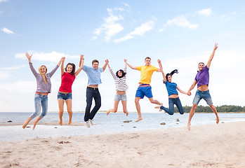 Image showing group of friends jumping on the beach