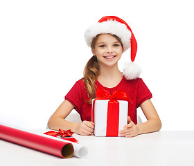 Image showing smiling girl in santa helper hat with gift box