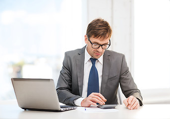 Image showing businessman with computer, papers and calculator