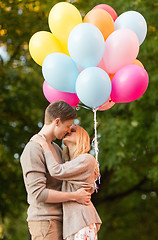 Image showing couple with colorful balloons kissing in the park