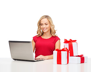 Image showing woman with gift boxes and laptop computer