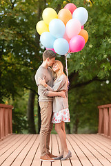 Image showing couple with colorful balloons kissing in the park