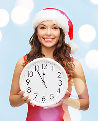 Image showing woman in santa helper hat with clock showing 12