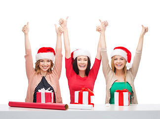 Image showing smiling women in santa helper hats with gift boxes