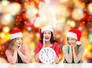 Image showing women in santa helper hats with clock showing 12