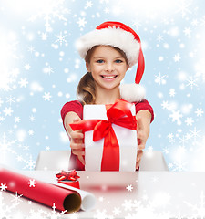 Image showing smiling girl in santa helper hat with gift box