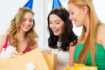 Image showing three smiling women in blue hats with gift boxes