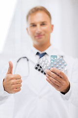 Image showing male doctor with packs of pills