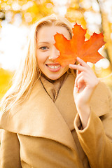 Image showing woman with red marple leaf in the autumn park