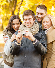 Image showing group of friends with photo camera in autumn park