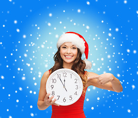 Image showing woman in santa helper hat with clock showing 12