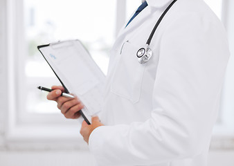 Image showing male doctor with stethoscope writing prescription