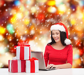 Image showing woman with gift boxes and laptop computer