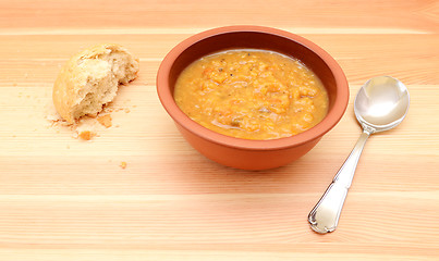 Image showing Half-eaten bread roll with a bowl of vegetable soup