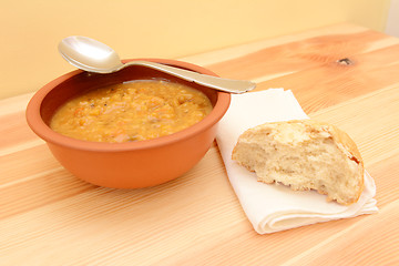 Image showing Bowl of soup, with a half-eaten bread roll on a serviette 