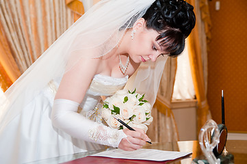Image showing Pretty bride signing document