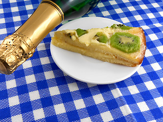 Image showing kiwi tasty cake close up at plate and champagne bottle