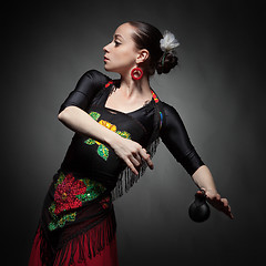 Image showing young woman dancing flamenco with castanets on black