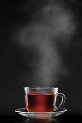 Image showing cup with hot tea and steam on black