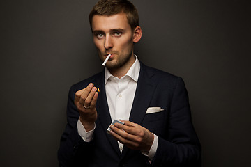 Image showing portrait of handsome businessman with cigarette on black