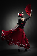 Image showing young woman dancing flamenco on black