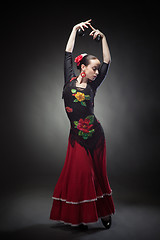 Image showing young woman dancing flamenco with castanets on black