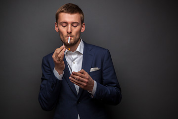 Image showing portrait of handsome businessman with cigarette on black