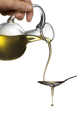 Image showing Pouring oil from jar on spoon isolated on white