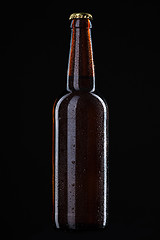 Image showing Beer bottle with water drops isolated on black