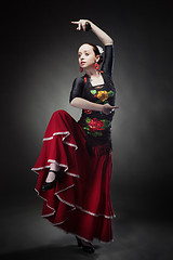 Image showing young woman dancing flamenco with castanets on black