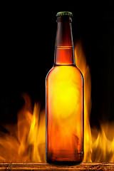 Image showing Beer bottle in fire on black