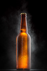 Image showing Cold beer bottle with drops, frost and vapour on black