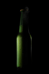 Image showing Green beer bottle with drops and open cup on black