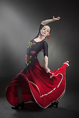 Image showing young woman dancing flamenco on black
