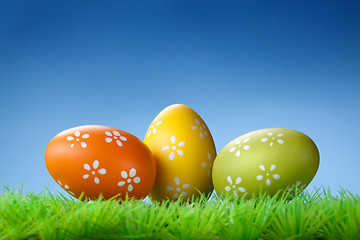 Image showing Color easter eggs in the grass on blue