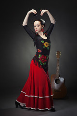 Image showing young woman dancing flamenco with castanets on black