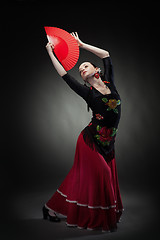 Image showing young woman dancing flamenco on black