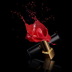 Image showing red lipstick with splash of paint isolated on black