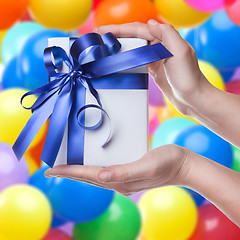 Image showing Hands holding gift in package with blue ribbon