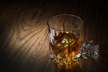 Image showing Whiskey with ice in glass on the wood