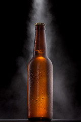 Image showing Cold beer bottle with drops, frost and vapour on black