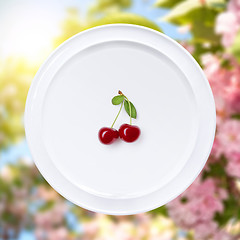 Image showing Cherry on white plate against sakura flowers