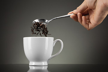 Image showing tea pour out into white cup on grey