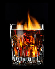 Image showing cola with cognac and fire in glass on black