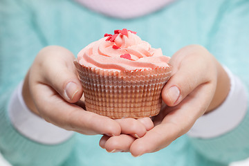 Image showing Woman holding a pink cupcake on white