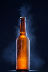 Image showing Cold beer bottle with drops, frost and vapour on black