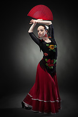 Image showing young woman dancing flamenco on black