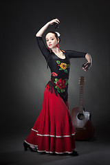 Image showing young woman dancing flamenco with castanets on black