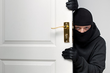 Image showing Burglar sneaking in a open house door